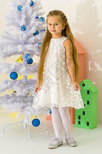 穿着时尚服装的女孩坐在圣诞树前的地板上 笑声针叶树假期礼物装饰品装饰枞树装潢庆典童年幸福图片