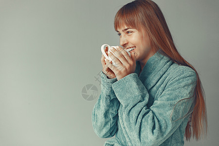 美丽的女孩站在蓝浴袍的摄影棚里女性头发女士蓝色喜悦工作室杯子咖啡成人冒充图片