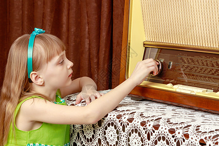 女孩在旧收音机上打开音量键盘频率童年技术女性冒充音乐幸福调频控制体积图片