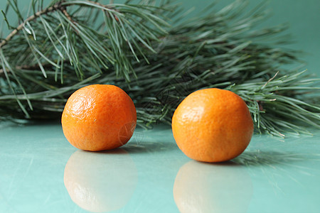 绿色背景中云杉树的树枝旁边 有两三个未剥皮的柑橘 圣诞跨年夜气氛异国情调木头水果宏观桌子甜点团体食物果汁背景图片