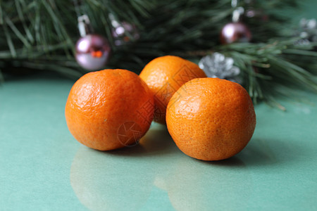 绿色背景中云杉树的树枝旁边 有两三个未剥皮的柑橘 圣诞跨年夜气氛宏观健康饮食水果异国橙子食物柑桔桌子团体背景图片