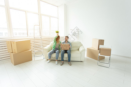 搬家 搬迁和新的家庭概念     年轻夫妇在沙发上玩得开心 围着盒子房间男朋友公寓财产女士抵押住房夫妻女朋友骑术图片