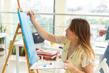 艺术课 绘画和创造性概念     女学生坐在装有调色板和油漆刷的垫子前教育工艺职业大学艺术品画家画架想像力创造力艺术生图片