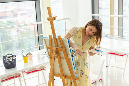 艺术课 绘画和创造性概念     女学生坐在装有调色板和油漆刷的垫子前美术教育职业天赋女性工作室课程学校大学想像力背景图片