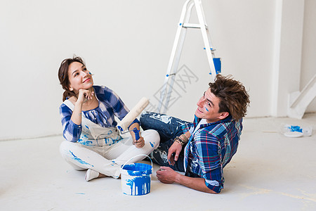 人与内地概念坐在白地板上的年轻夫妇和夫妻乐器牛仔裤女士微笑墙纸改造梯子胶水衬衫图片