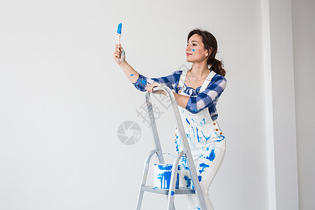 人 翻修和工作概念     站在梯子上和壁画墙上的美女设计师装修维修房子墙纸夫妻装潢师改装格子胶水图片