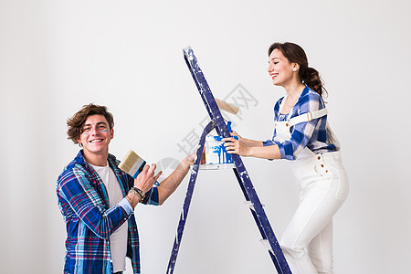 人 重新装配和修理概念可爱的年轻夫妇在新公寓里进行翻新墙纸乐器女孩衬衫男性装潢师梯子工具夫妻维修背景图片