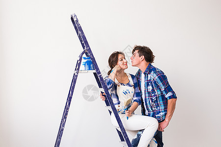 人 装修和维修概念  年轻夫妇在新公寓里重新装修和接吻画笔楼梯潮人胡子工作男人滚筒梯子工人情绪图片
