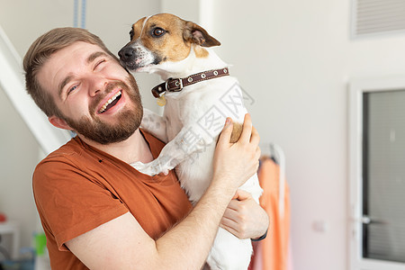 动物 宠物和人的概念  穿着休闲芥末 T 恤 带着杰克罗素梗犬的微笑男人拥抱猎犬快乐工作室男性朋友胡须乐趣哺乳动物小狗图片