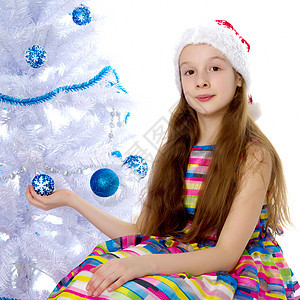 有个小女孩在装饰圣诞树呢针叶蜡烛枞树装饰品假期幸福庆典女孩装潢礼物图片