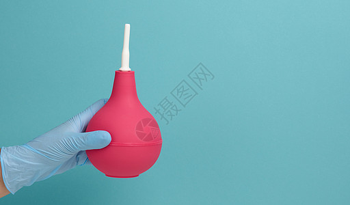 蓝色医用手套上戴着蓝底的粉红色橡胶灌肠护士诊所药店医生考试直肠空气灯泡注射女性图片