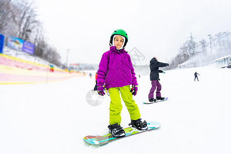 小可爱女孩滑雪 在滑雪胜地 阳光明媚的冬天快乐闲暇滑雪板孩子速度微笑乐趣童年头盔运动员图片