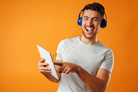英俊的青年混合种族男子 用蓝耳机收听音乐成人男性快乐拉丁微笑工作室男人图片