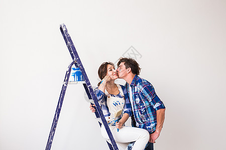 人 装修和维修概念  年轻夫妇在新公寓里重新装修和接吻梯子刷子装潢师帽子女士房子建筑楼梯幸福家庭图片