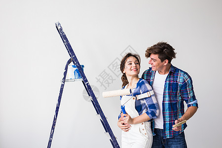 人 重新装配和修理概念可爱的年轻夫妇在新公寓里进行翻新梯子衬衫维修牛仔裤男人女性男性女士墙纸夫妻背景图片