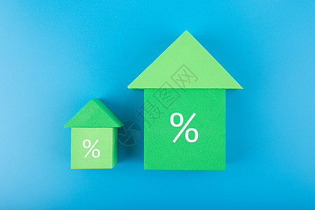 两座由玩具砖制成的绿屋 蓝色背景上的百分数符号增加图片