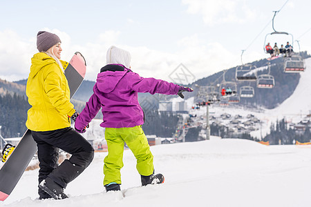 母亲和女儿带着雪板在雪中玩耍季节青少年运动活动高山滑雪喜悦童年缆车女性图片