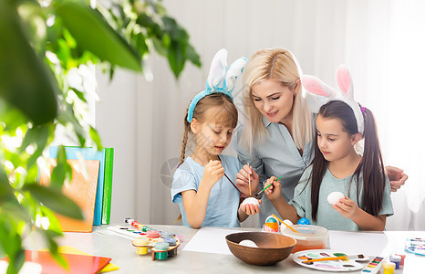 年轻母亲和两个女儿在复活节鸡蛋上画画创造力女孩幸福姐姐艺术兄弟绘画父母装潢微笑图片