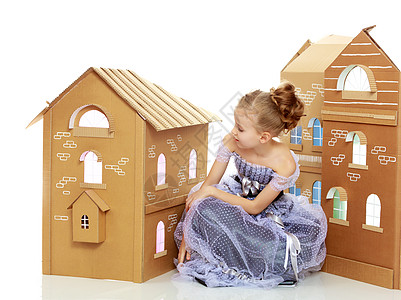 女孩在一栋由纸板制成的房子旁边摆姿势房间乐趣婴儿地面生活幸福公寓家庭快乐女士图片
