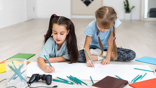 孩子们放学后做有创意的功课 在家庭地板上躺着 用彩色铅笔在纸上画画快乐绘画艺术童年学校教育朋友们幼儿园蜡笔地面图片