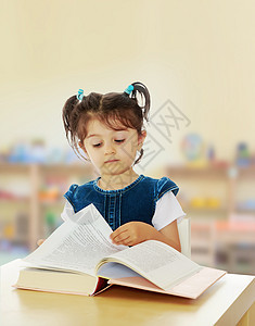小女孩在桌子上看一本书知识架子孩子们材料童年教育孩子乐趣玩具学校图片