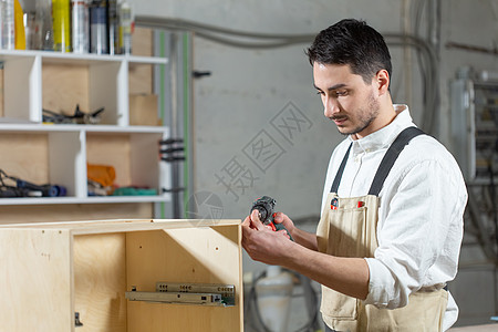 家具厂 小型公司和人的概念  青年工人在一家生产家具的工厂工作工艺职业木工木材商业技术制造业男人机器工具图片