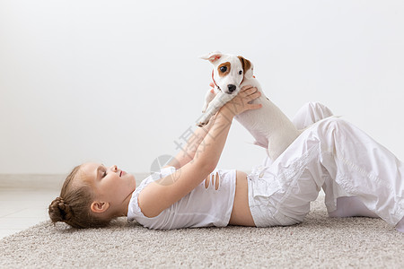 人 宠物和动物概念  小女孩坐在白色背景的地板上 抱着小狗杰克罗素梗犬乐趣地面猎犬黑发婴儿运动鞋犬类孩子友谊幸福图片