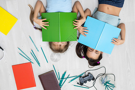 人 孩子 朋友 文学和友谊概念  两个快乐的女孩躺在地上 在家看书童年青少年家庭作业房间朋友们教育读者阅读享受女孩们图片