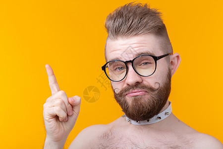 黄色背景上留着胡子和胡须 没有衬衫和眼镜的风趣年轻人 非标准广告的概念图片
