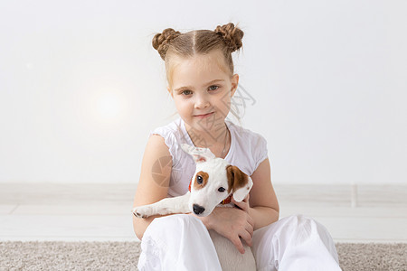 人 宠物和动物概念  小女孩坐在白色背景的地板上 抱着小狗杰克罗素梗犬孩子运动鞋婴儿幸福黑发犬类地面猎犬友谊乐趣图片