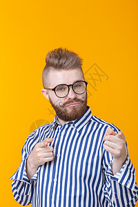 留着小胡子 戴着眼镜的滑稽年轻人在黄色背景下向你展示 非标准广告的概念成人男性胡须乐趣青年姿势男生身体快乐艺术图片
