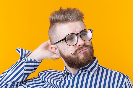 一个积极的年轻男学生的画像 他的发型很时髦 戴着眼镜 留着黄色背景的胡子 男士理发店概念和美容院头发姿势青年乐趣男生快乐艺术潮人图片