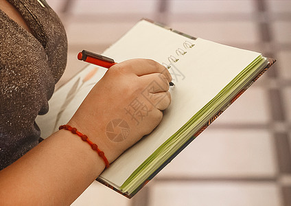 女孩的手拿着笔 在笔记本上写文字和设计特写写作职场报告教育桌子记事本女性文书备忘录铅笔图片