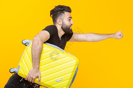 可爱漂亮的年轻阿拉伯男子留着胡子 手里拿着一个黄色的手提箱 背景是黄色的 旅行和假期的概念男性身体人士商务潮人快乐头发艺术乐趣青图片