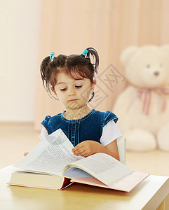 小女孩在桌子上看一本书乐趣玩具知识快乐孩子学校女学生学生图书女孩图片