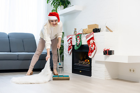女人打扫房子 穿着圣塔帽的有趣的女孩 圣诞节时间和家务概念图片