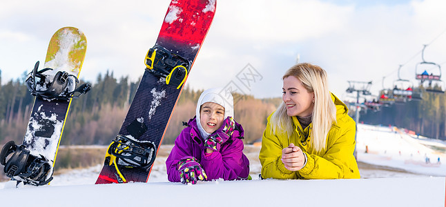 母亲和女儿带着雪板在雪中玩耍幸福童年活动闲暇季节行动假期滑雪者女士缆车图片