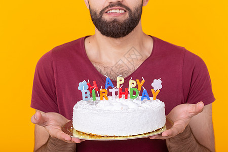 身份不明的年轻男性嬉皮士留着胡子 手里拿着一块蛋糕 上面写着生日快乐 祝贺周年纪念日和节日 促销和折扣的概念图片