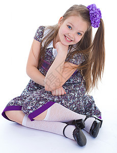 可爱的小女孩坐在地板上微笑腰带女孩背包衬衫学校裙子紫色孩子金发女郎图片