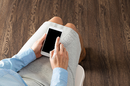 手提电话在大腿上的商业妇女阅读互联网软垫男人手指触摸屏技术女性工具杯子图片