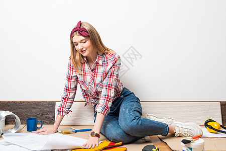 带着蓝图坐在地板上的快乐女孩女性工作建筑设计师建筑学微笑绘画衣服工具衬衫图片