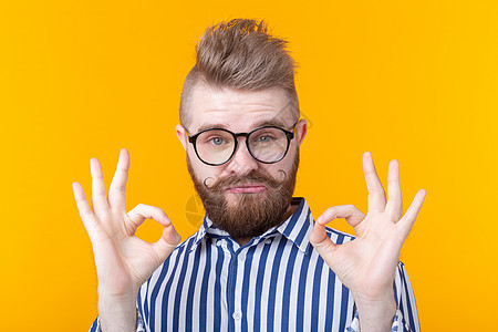 长着胡子的帅小伙和戴眼镜的胡须显示 在黄色背景上摆姿势不错 运气和理发店的概念节目头发艺术青年人士男生商务男性乐趣潮人图片