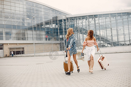 两个美丽的女孩站在机场旁边 站着成人女孩们女性女士游客快乐飞机航空公司国际行李图片