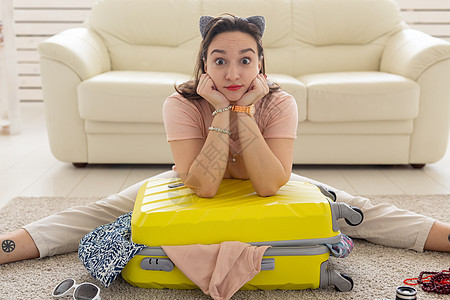 假日 旅行和旅行概念     妇女在家里收集一个黄色手提箱女孩帽子家具假期航程行李房间快乐旅游房子图片