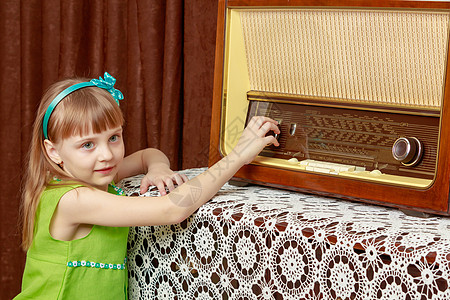 女孩在旧收音机上打开音量键盘调频微笑按钮女儿控制技术扬声器拨号冒充频率图片