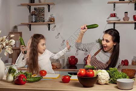 母亲和女儿正在做蔬菜沙拉 在厨房里玩得开心呢木板女士货架乡村女性黑发菜花成人父母灯泡图片