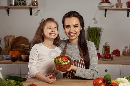母亲和女儿正在做蔬菜沙拉 在厨房里玩得开心呢货架食谱烹饪家庭父母乐趣女孩木板灯泡成人图片