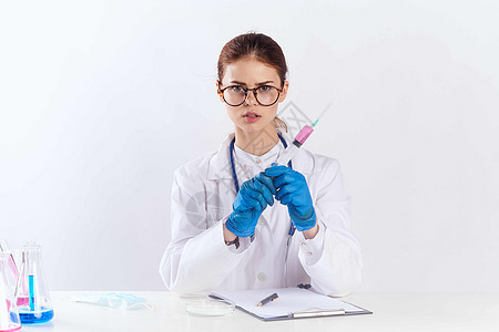 参加蓝手套药物测试的坐在桌边的女医生电脑化学家服务眼镜办公室桌子专家临床从业者药品图片