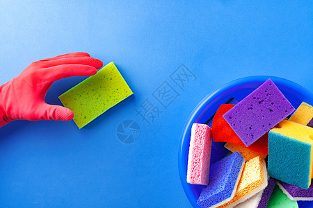 用蓝色背景的橡皮手套亲手发放用品 使用橡胶手套抛光服务家庭海绵瓶子厨房工具女士管家工作图片