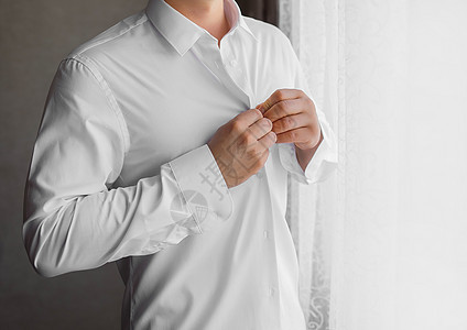 一个人在白色衬衫上扣纽扣 手放在窗外的灯光下衣服套装裙子人士按钮商务扣子经理夹克商业图片